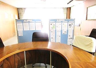 丸いか形の机と黒い椅子、展示ボードに書類などが貼られている写真