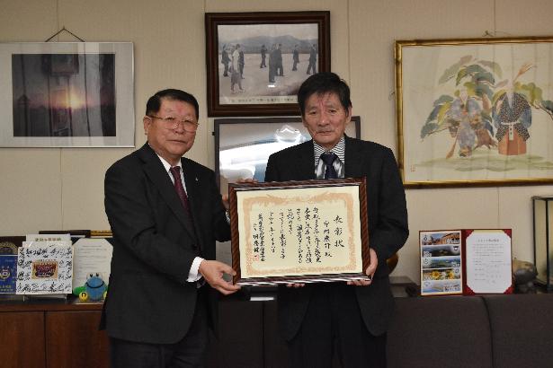 土地改良事業で功労者表彰をうけ表彰状を手に持つ中村さんと町長